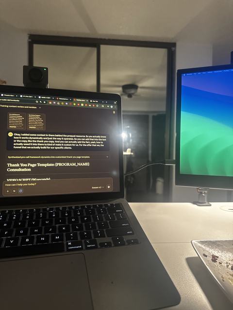 A laptop at night showing an AI chat drafting a page template, with a second monitor beside it