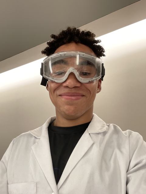 Phoenix in a lab coat and safety goggles, smiling