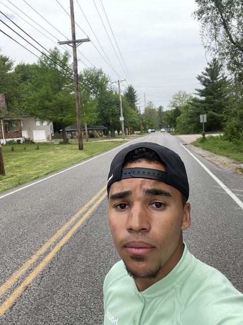 Phoenix in a backwards cap taking a selfie on an empty suburban road